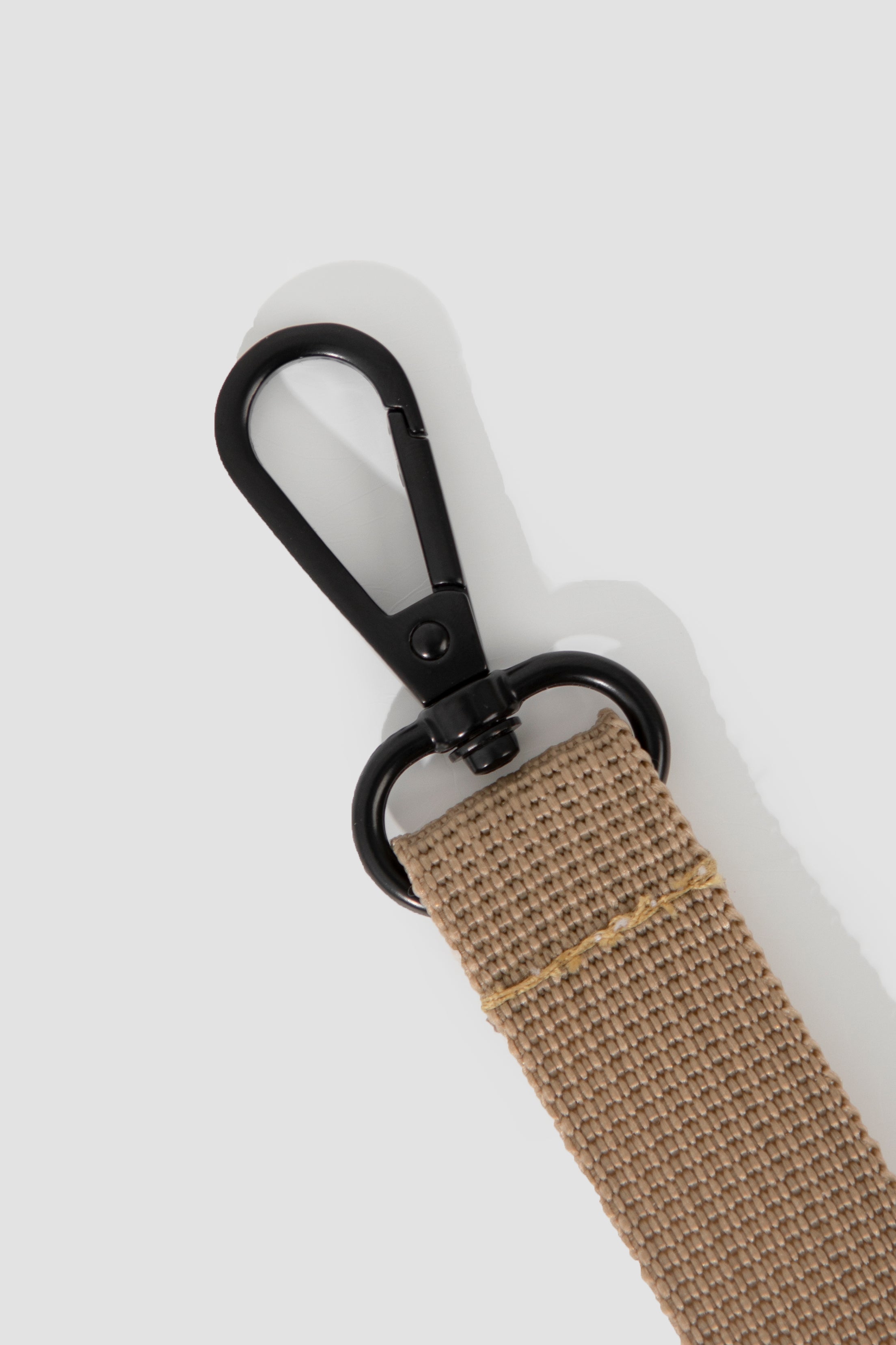 Beige strap with black metal clip on a white background