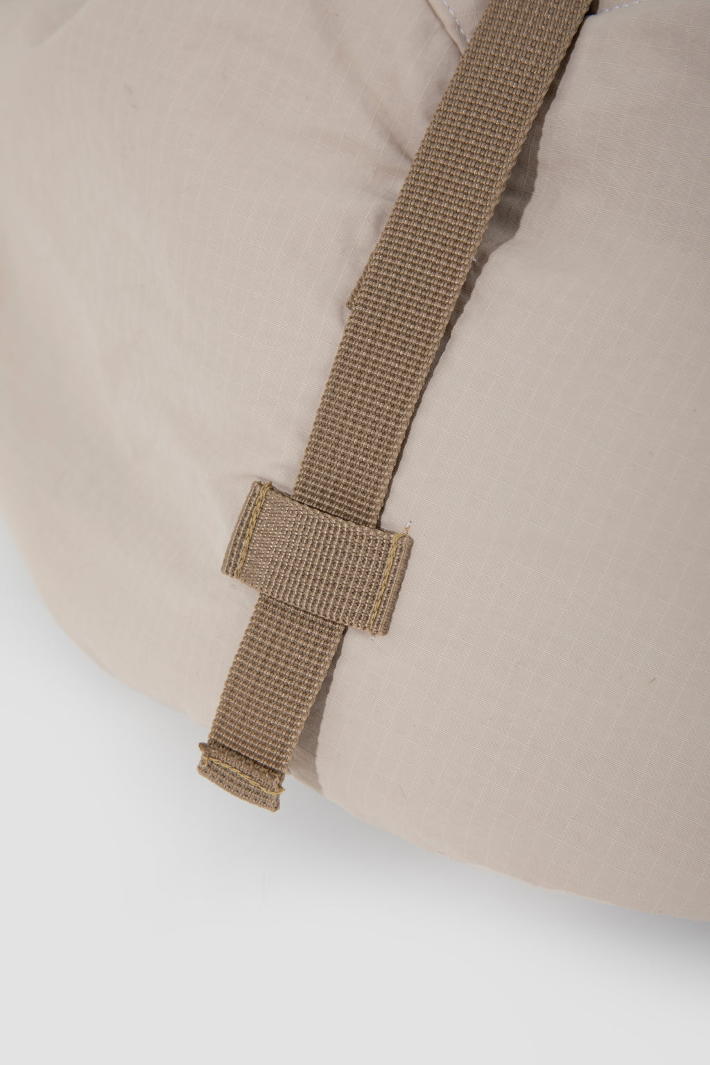 Close-up of a beige cushion with a brown strap and buckle on a white background