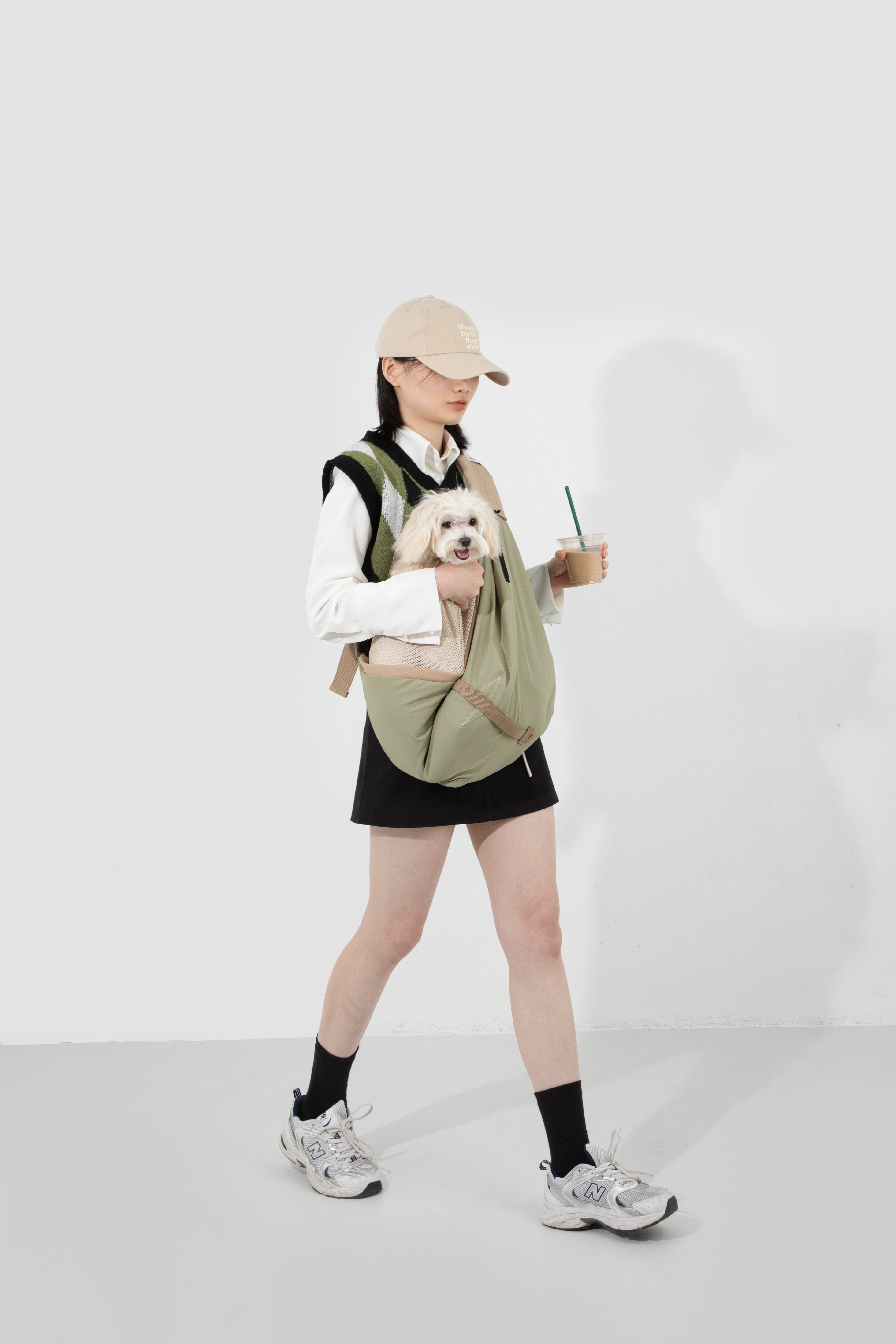 Person holding a small dog in a green bag against a white background
