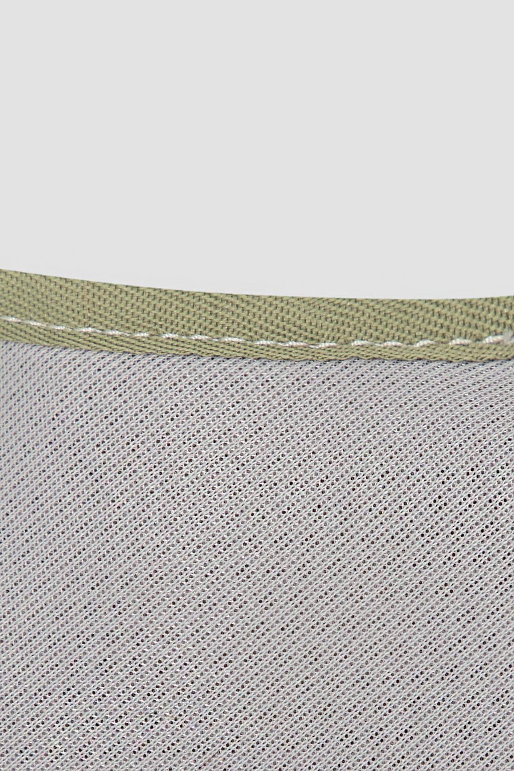 Close-up of a textured fabric with a green band on a light gray background