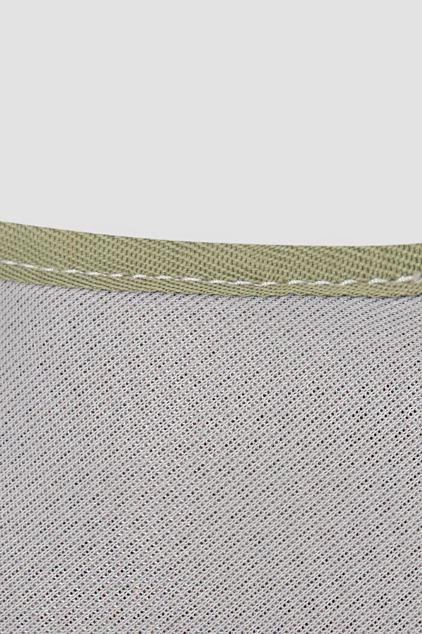 Close-up of a textured fabric with a green band on a light gray background