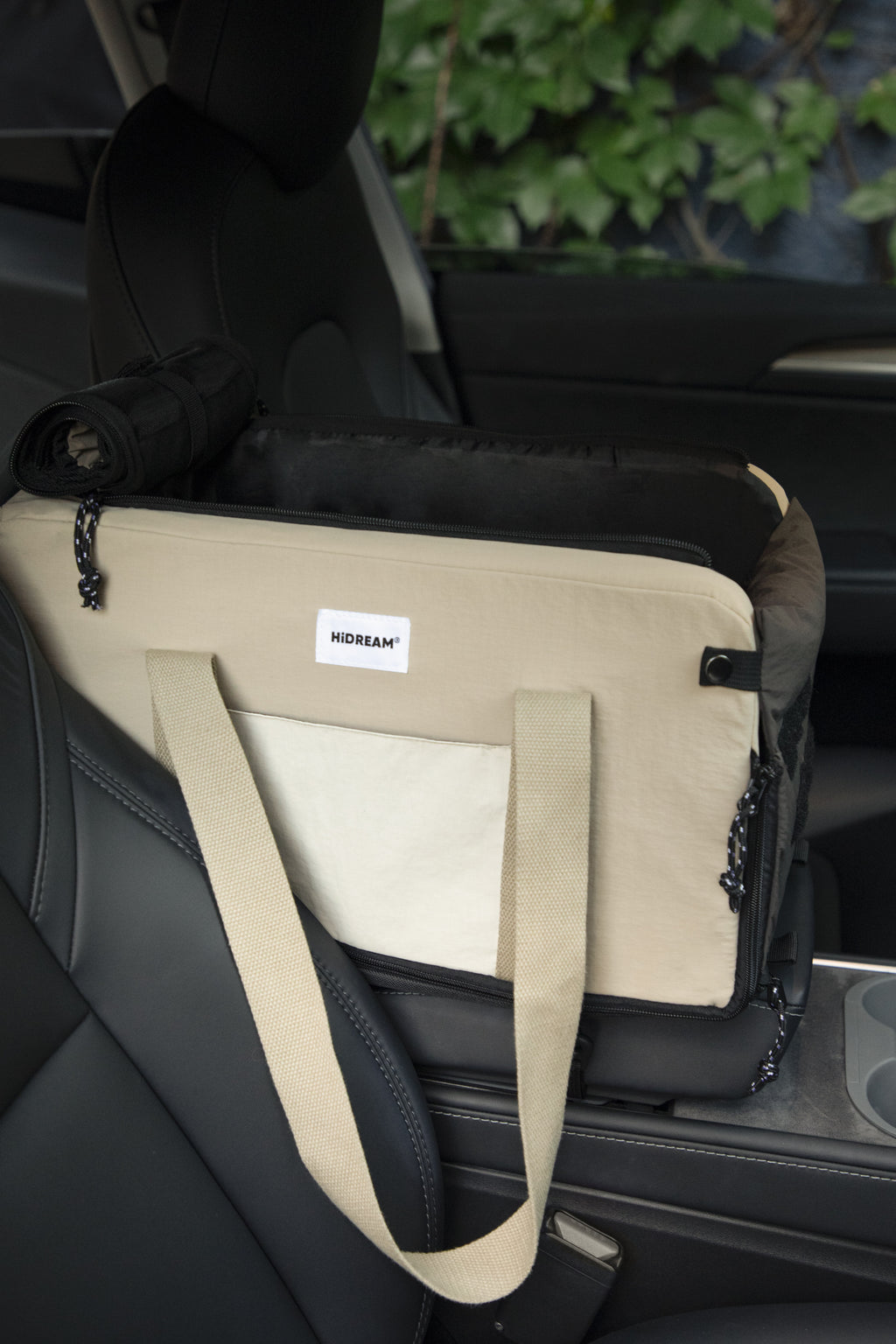 A beige and black pet car seat belt buckle carrier bag with a white 'HiDREAM' label, shown installed on a black car seat.