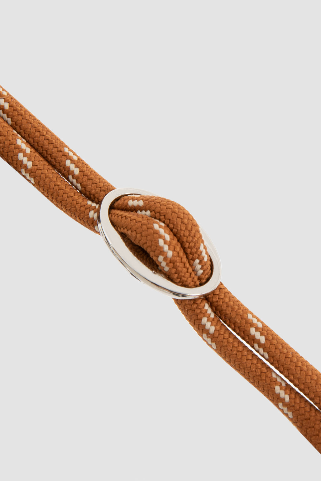 Close-up of brown rope with a silver knot on a light gray background