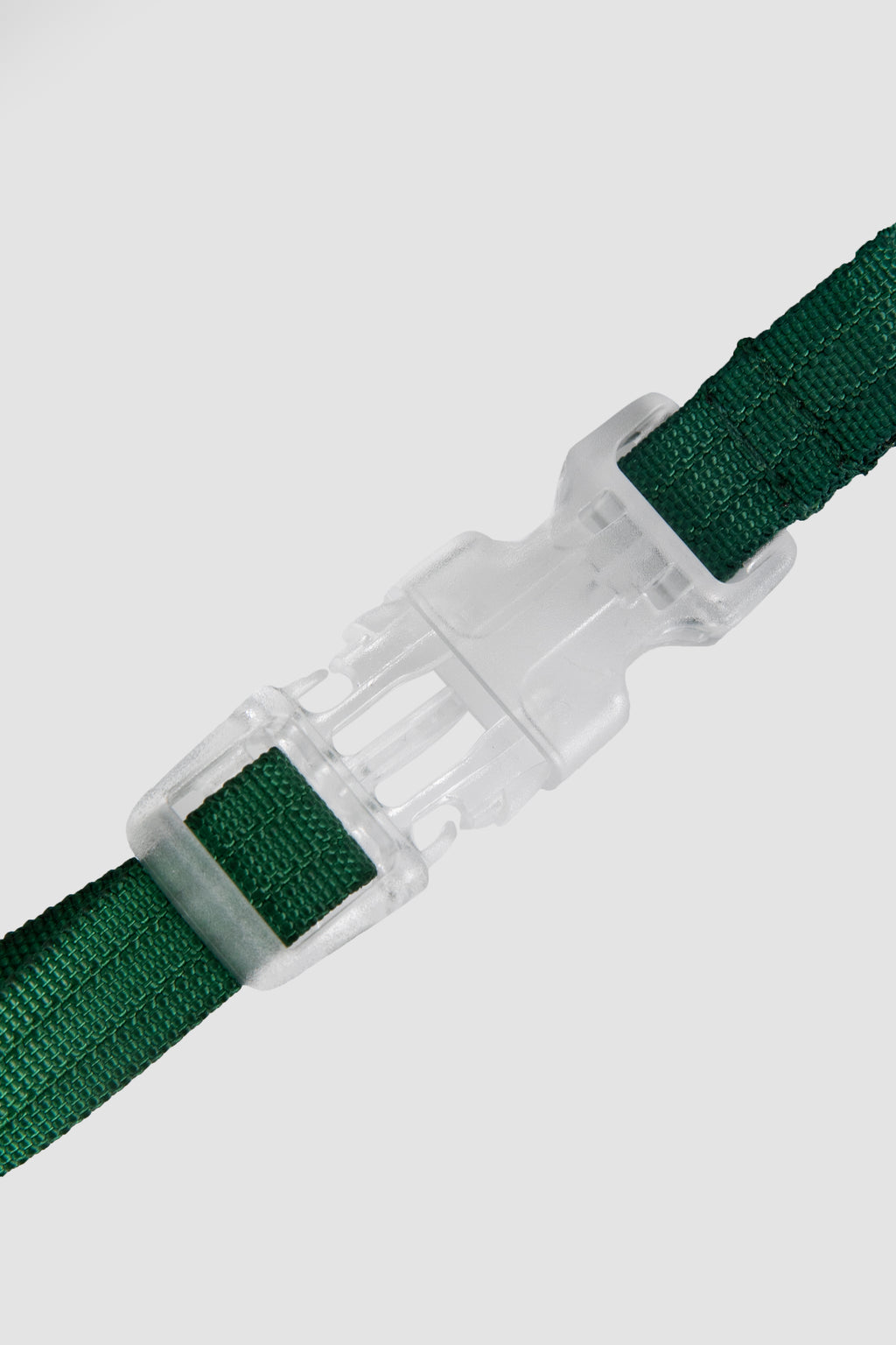 Green belt with a white plastic buckle on a light gray background