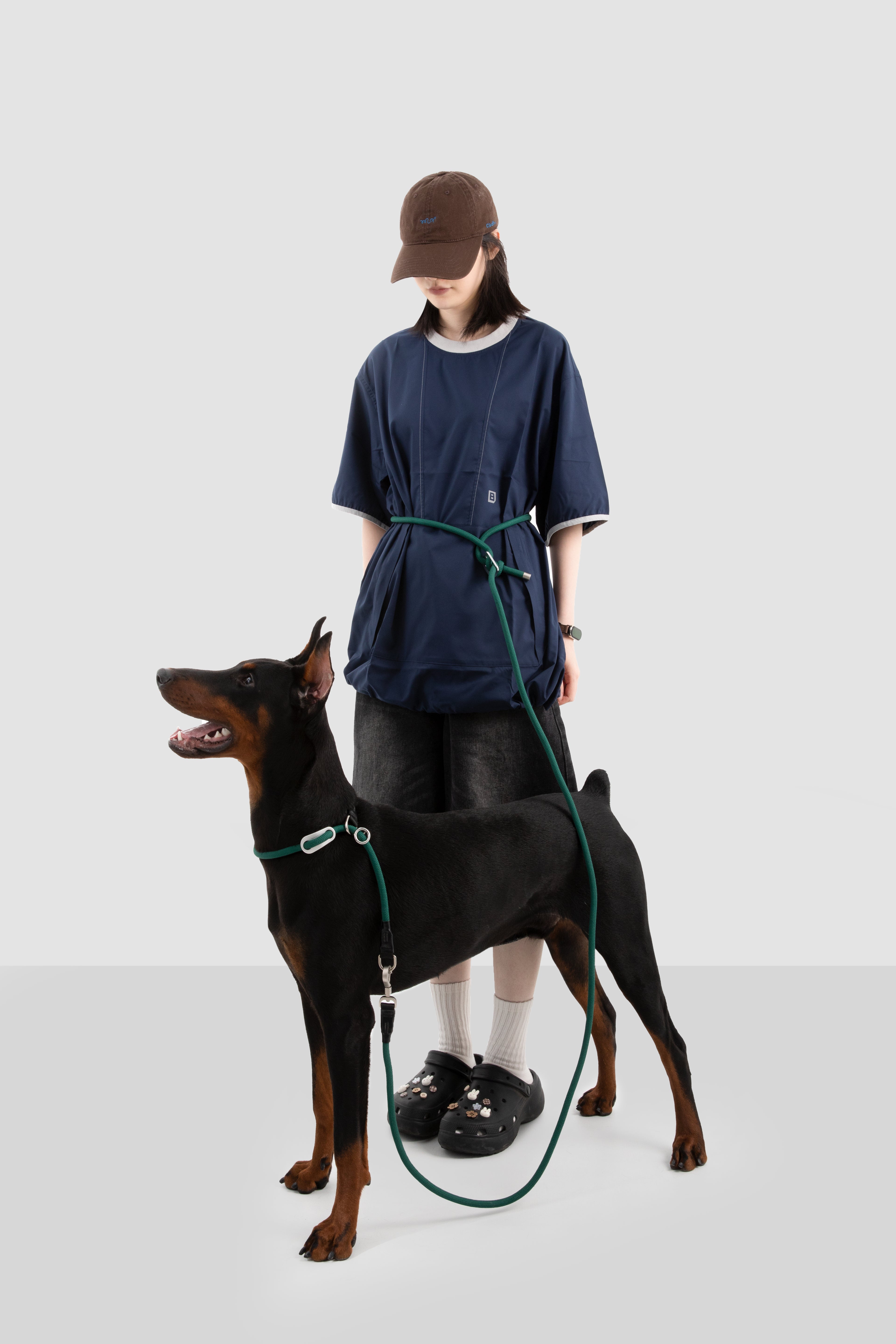 Person standing with a Doberman on a leash against a white background