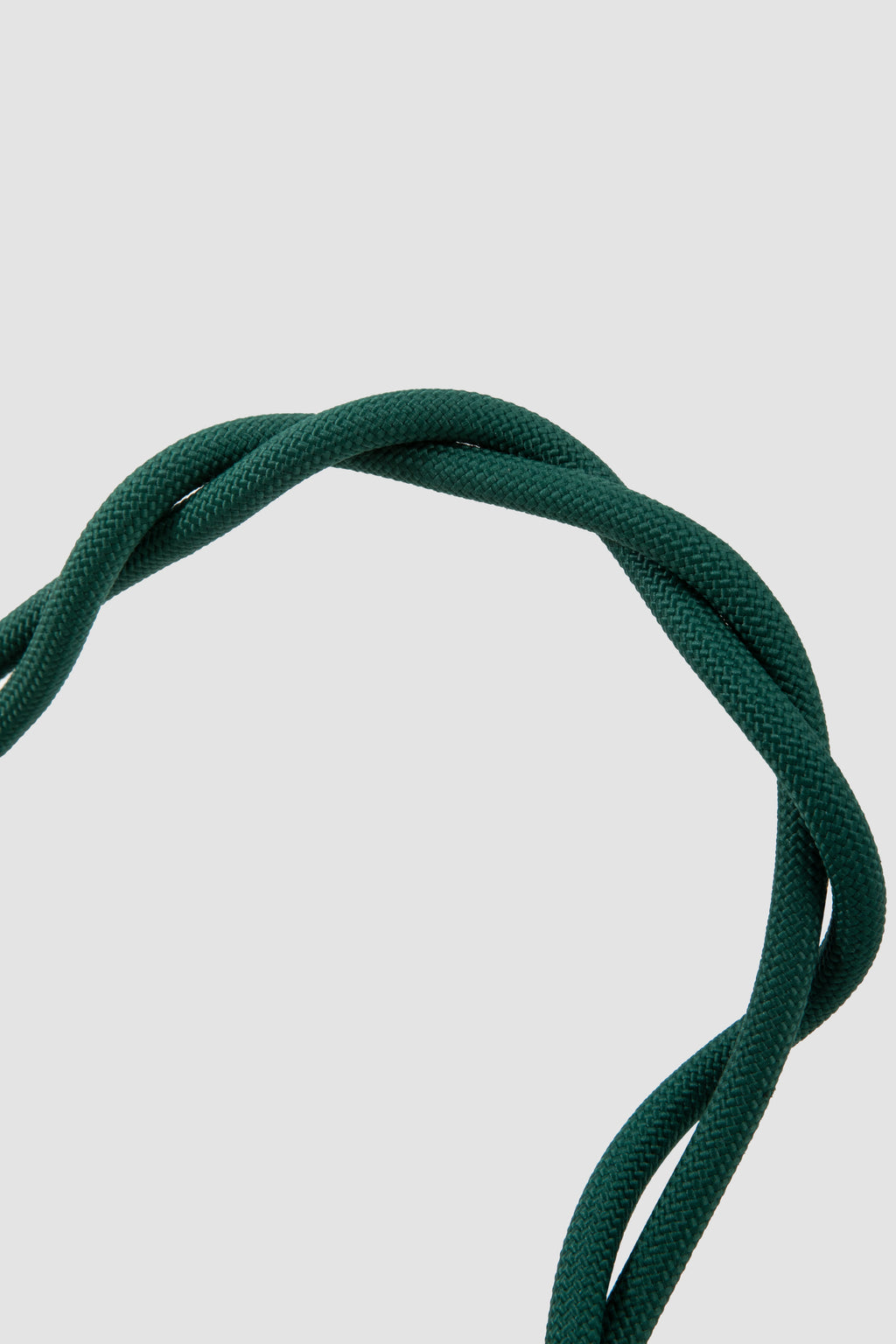 A close-up of a dark green braided or twisted cord arching over a light gray background.