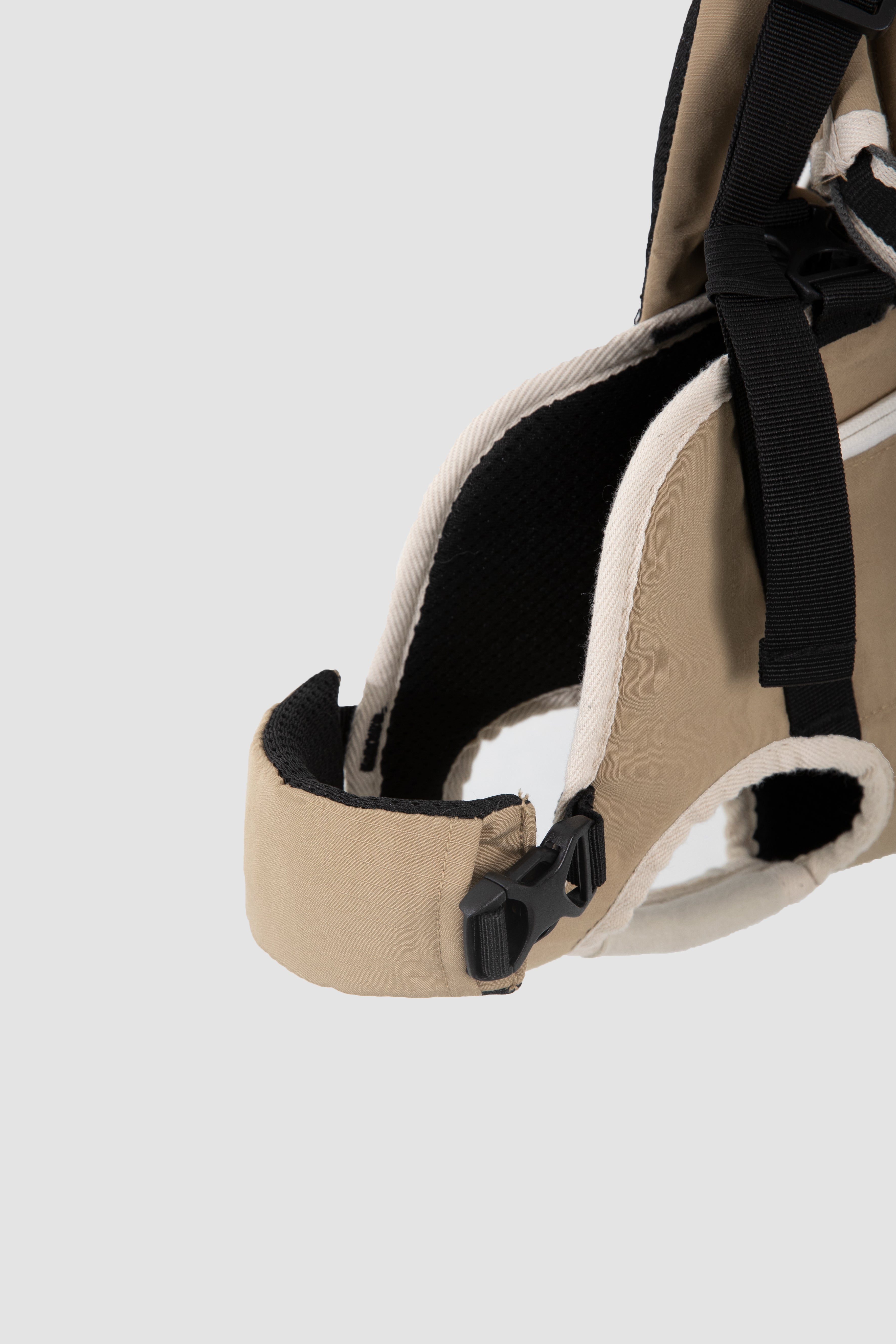 Close-up of a beige sandal with black straps on a light gray background