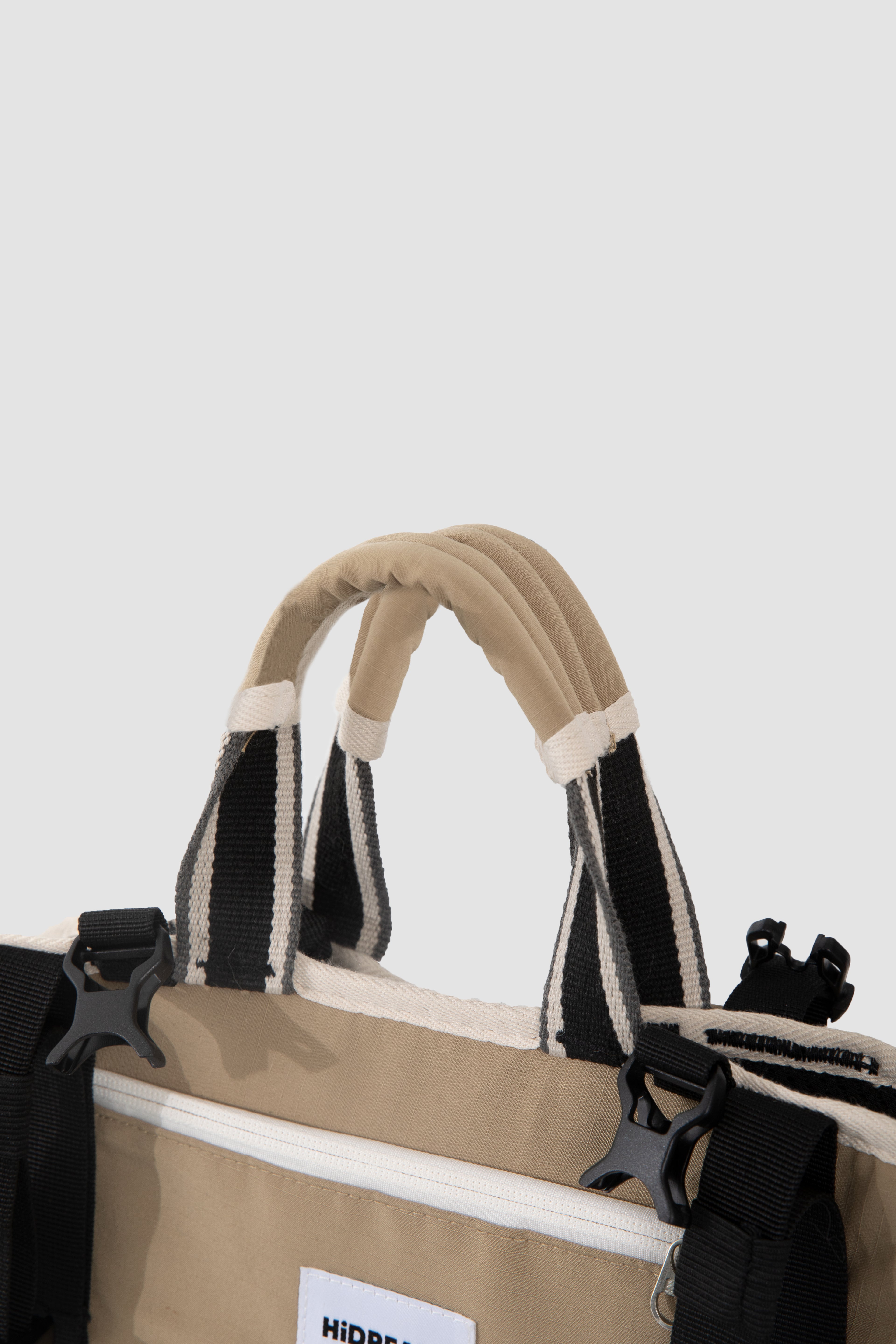 Close-up of a beige bag with black straps on a white background