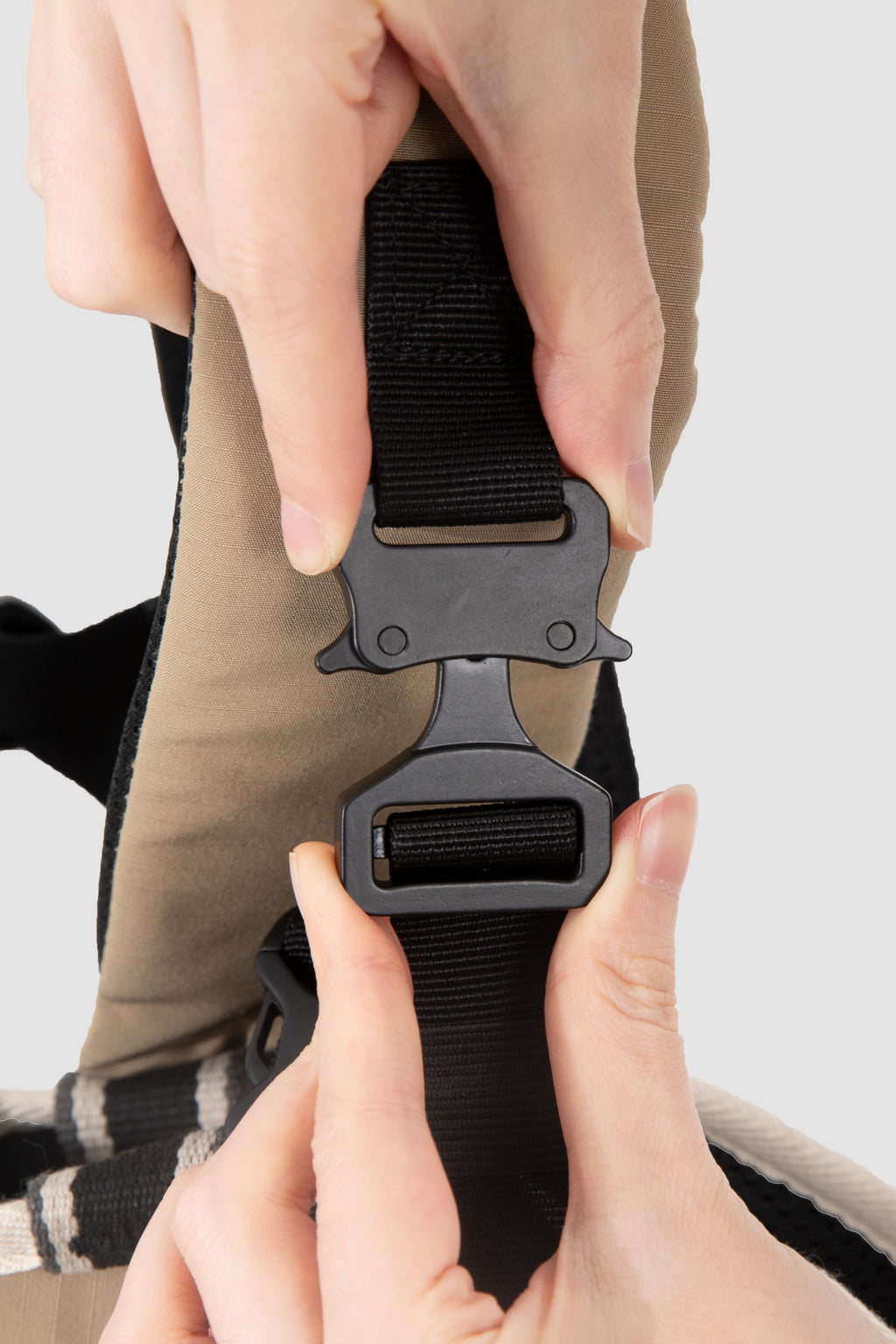 Close-up of hands adjusting a black belt buckle on a garment.