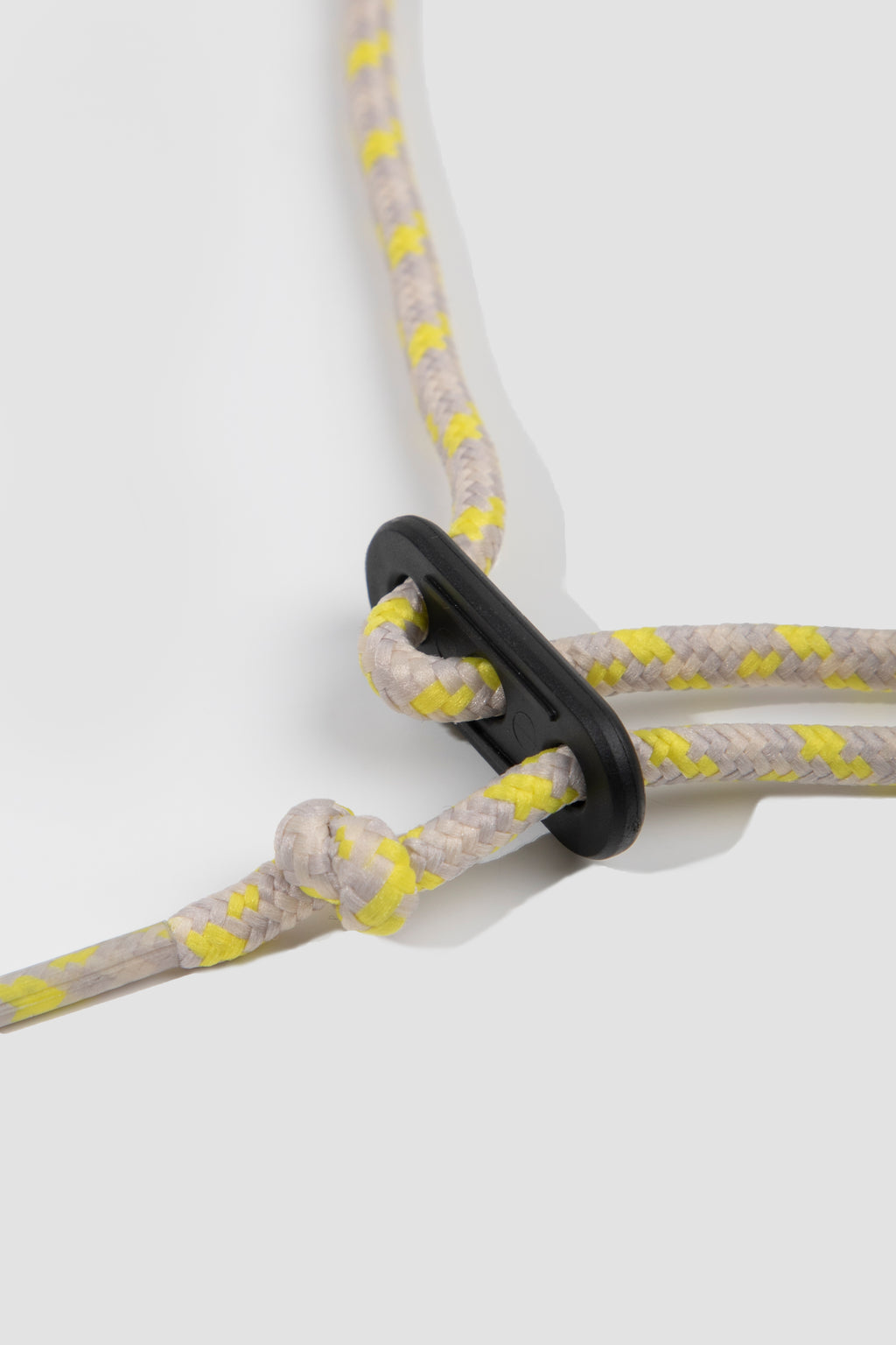 Close-up of gray and yellow rope with a black clip on a white background