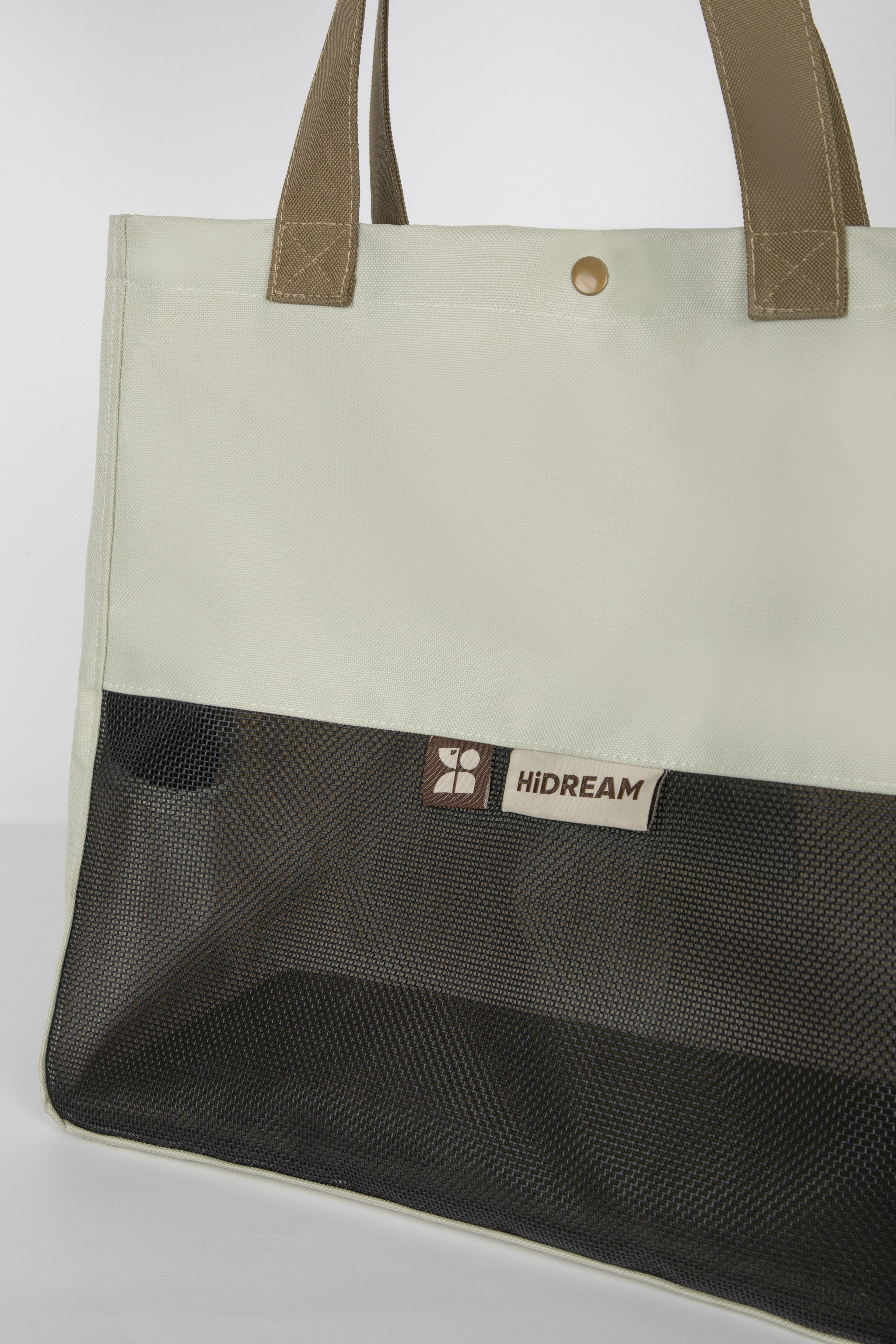 A large tote bag with a light beige upper section, brown shoulder straps, and a black mesh lower pocket. A small brand label reading HIDREAM is visible on the front.