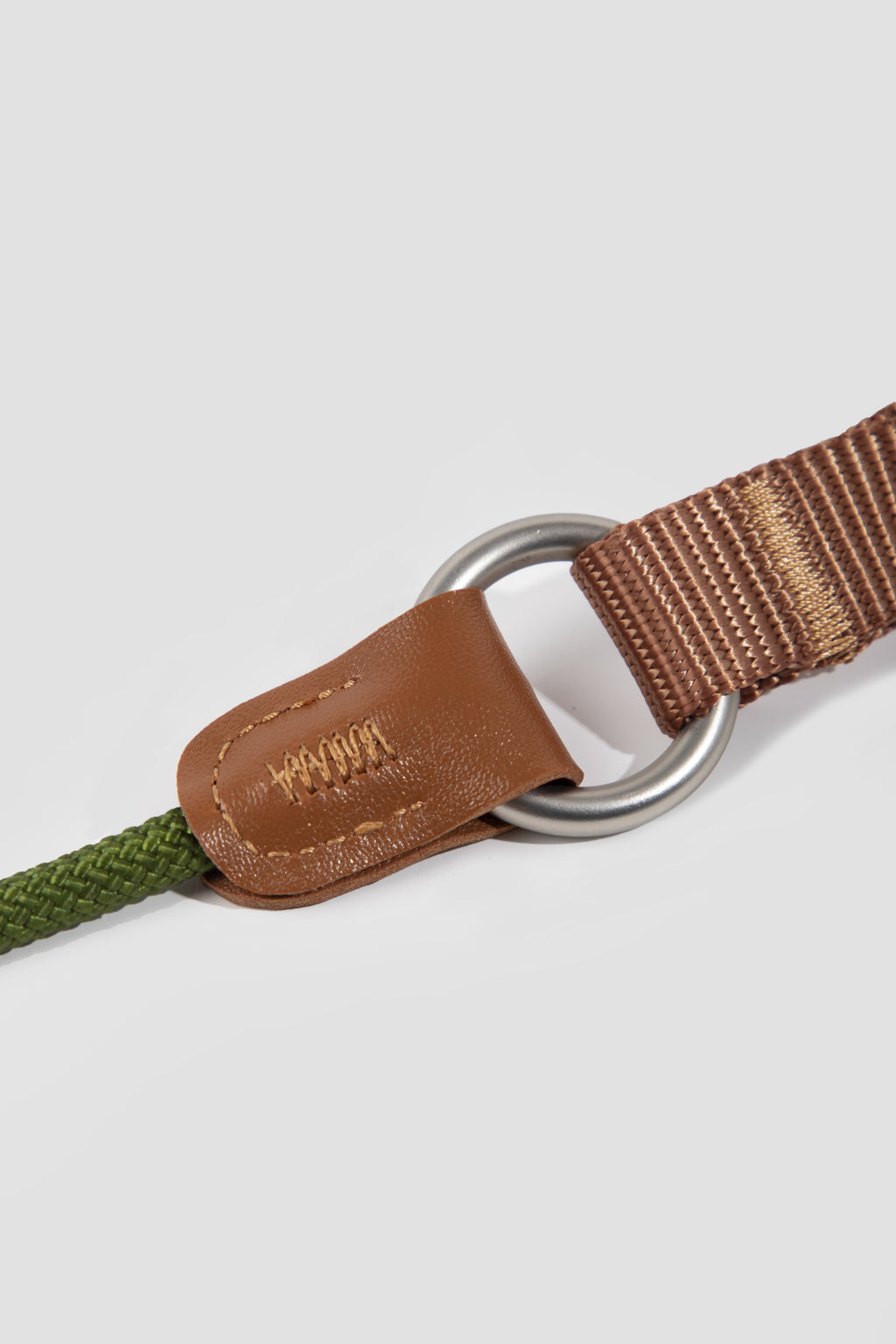 Close-up of a brown leather strap with metal ring on a light gray background