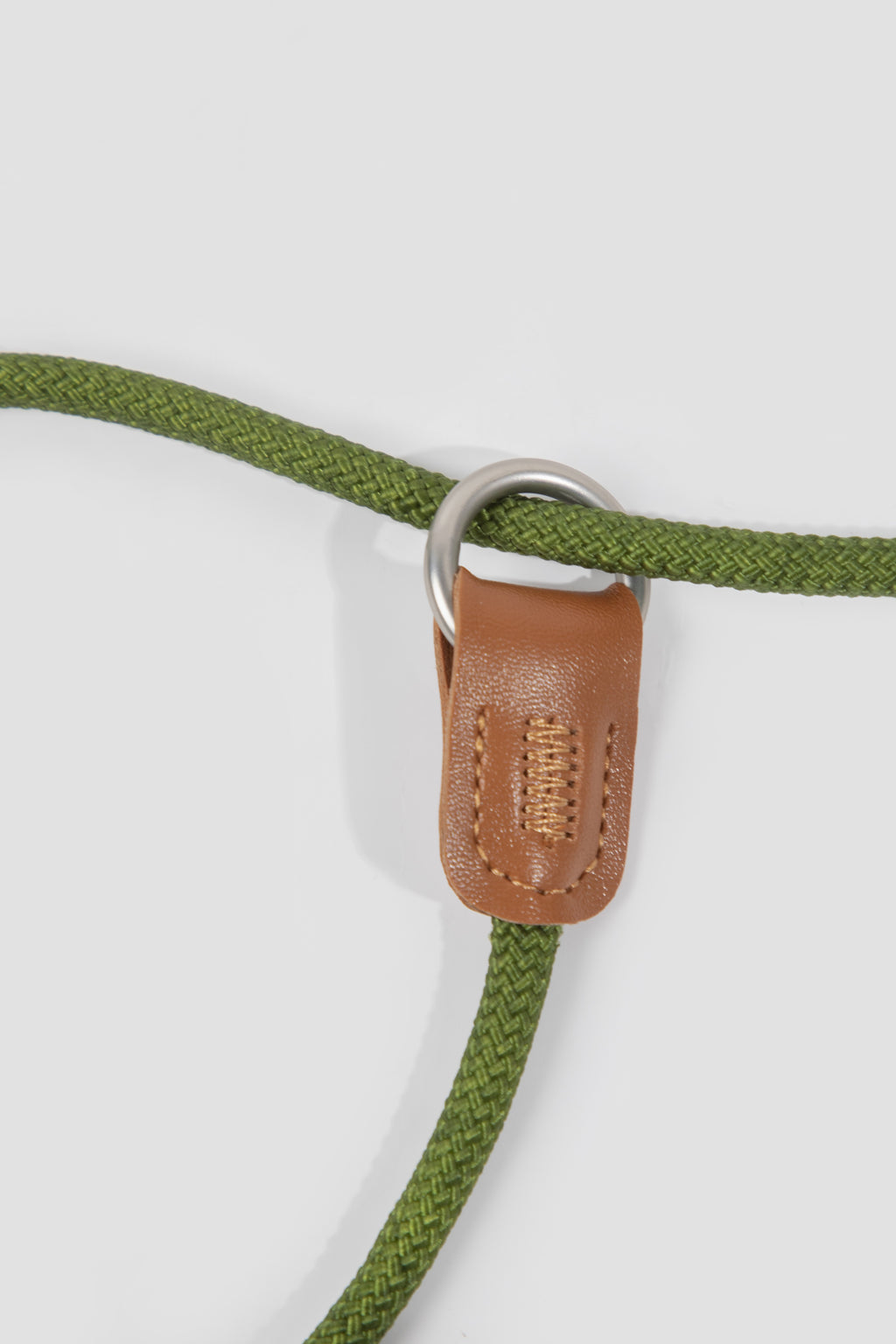 Green rope leash with brown leather patch and metal ring on a white background