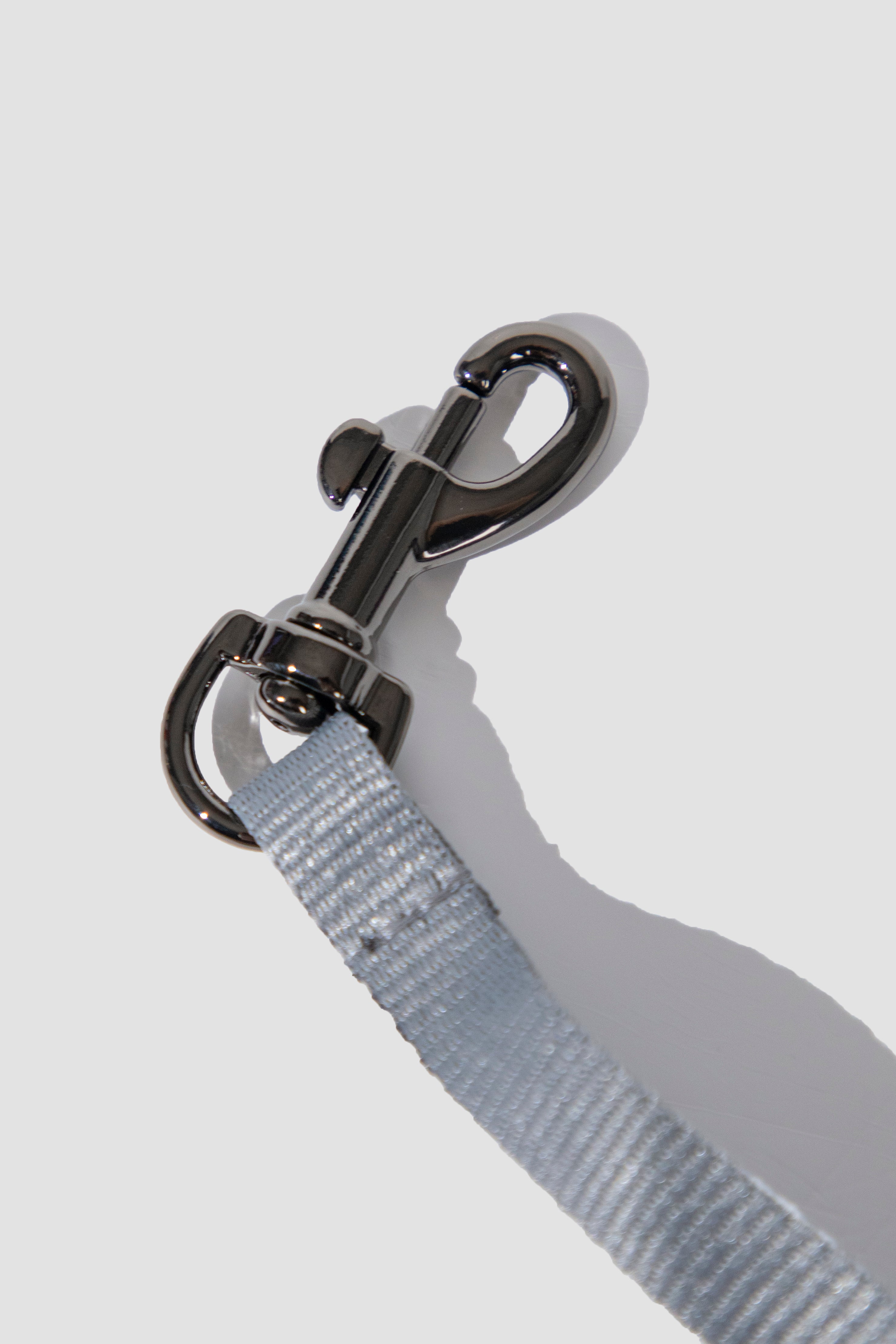A close-up of a light blue-gray woven strap attached to a polished silver metal swivel clasp, photographed on a clean light gray background.