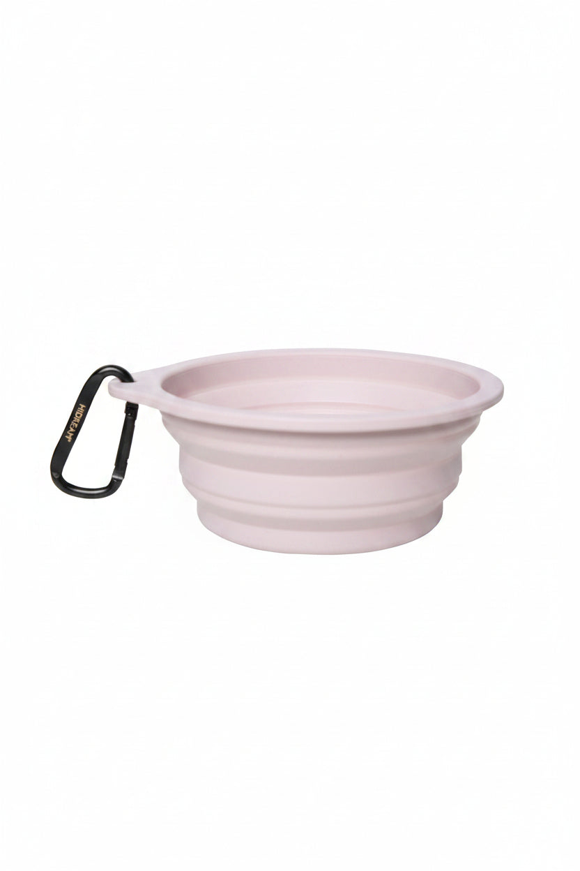 A light pink collapsible silicone pet bowl with a black carabiner clip on the side, shown on a plain white background.