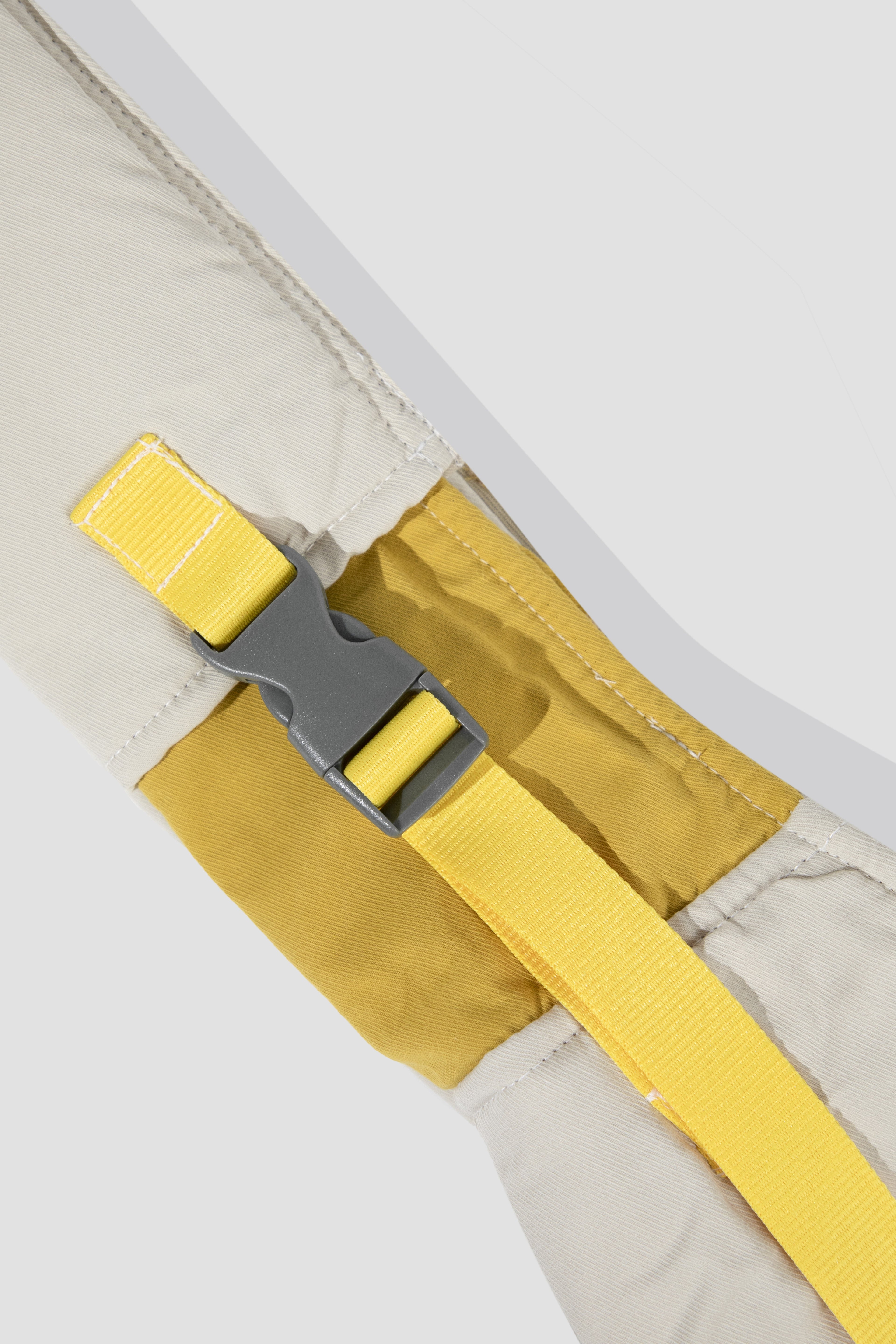 Close-up of a yellow strap with a gray buckle on a beige background